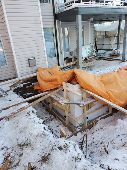 Advantage ICF frost wall covered with an orange insulated tarp after winter concrete pour, preventing heat loss during curing.