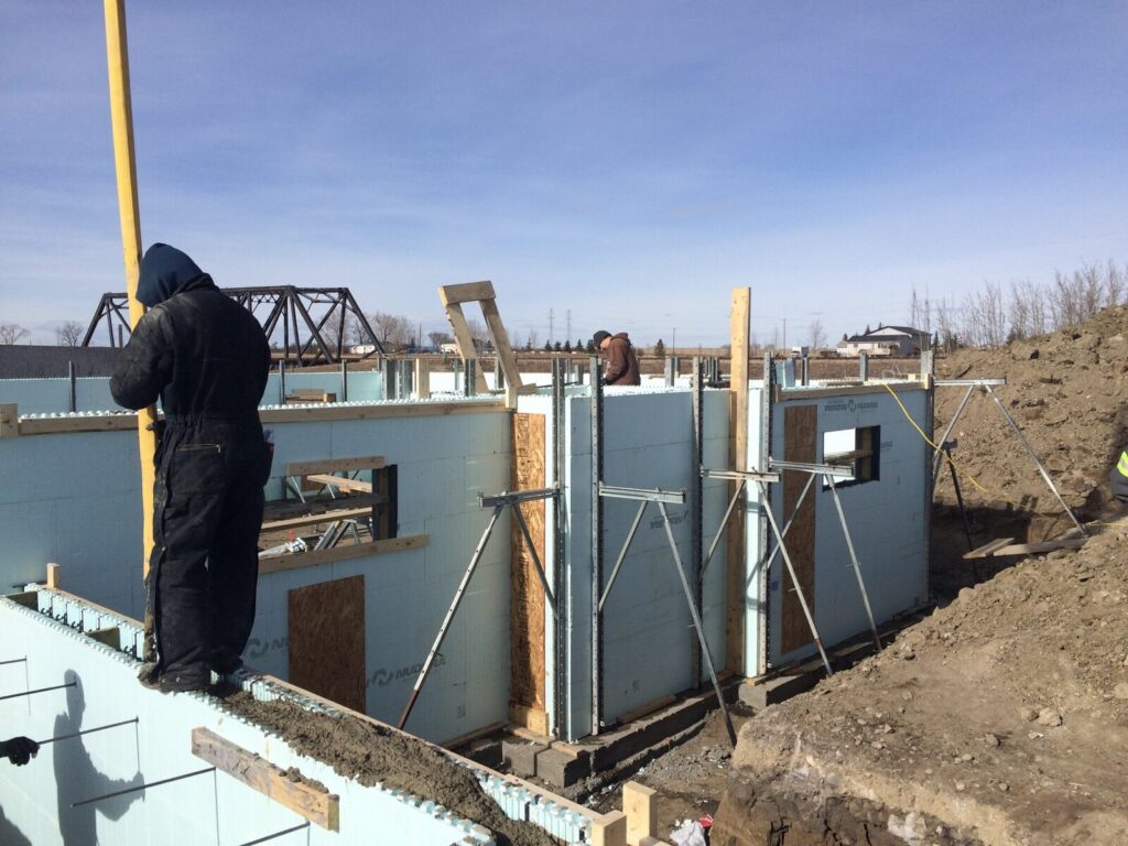 "A person pouring concrete into Nudura Insulated Concrete Form (ICF) blocks to lay the foundation for a sustainable and energy-efficient building."