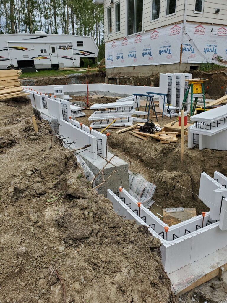 Advantage ICF step footing for a walk-out addition, showcasing the installation of frost wall blocks on top, ready to form a robust foundation for an existing home.