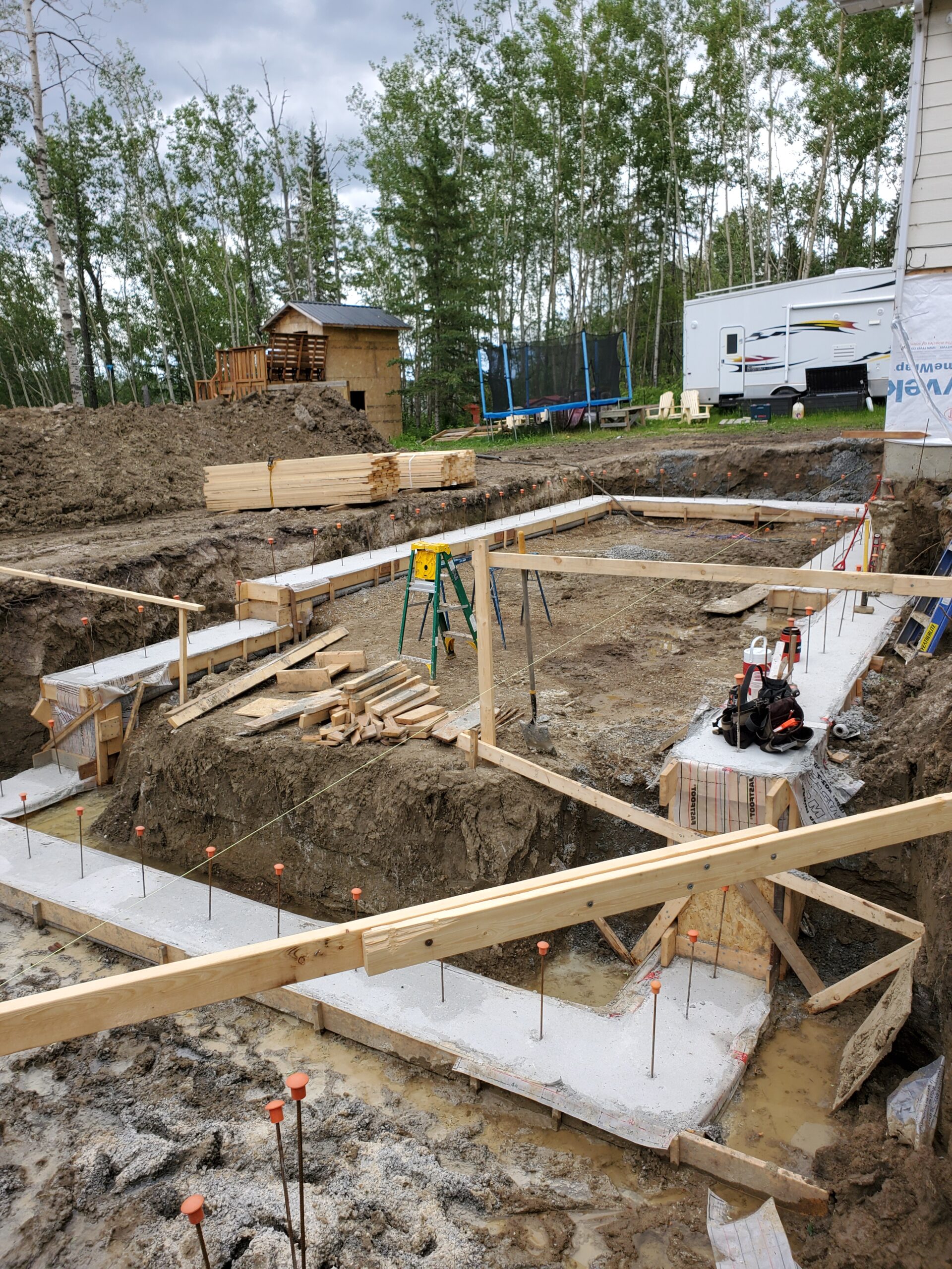 A step footing in progress for an Advantage ICF walk-out basement addition. The image illustrates the construction site, showcasing the carefully laid foundation using Insulated Concrete Forms. The stepped footing design is evident, highlighting the initial stages of the walk-out basement construction with Advantage ICF blocks.