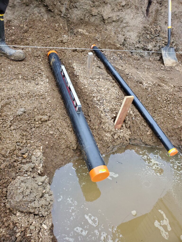 Drain pipe positioned beneath footing, connecting weeping tile to sump pump for optimal drainage.