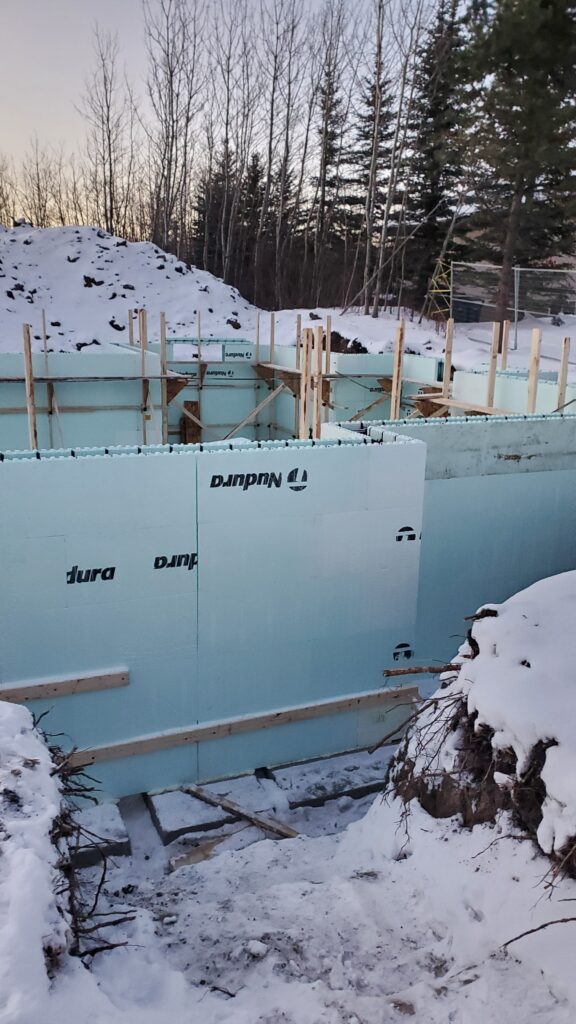 A detailed view of a residential Nudura ICF basement foundation under construction, highlighting the common seam in the center of the ICF wall.