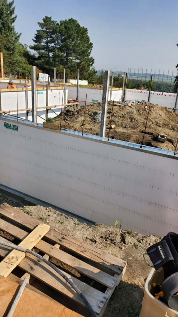 A Quad Lock ICF basement under construction in Edmonton, with white insulated concrete forms and wooden supports.